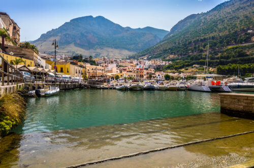 port boats and surrounding landscape in sicily castellammare del golfo with a fisherman's ramp and colourful houses up the shore