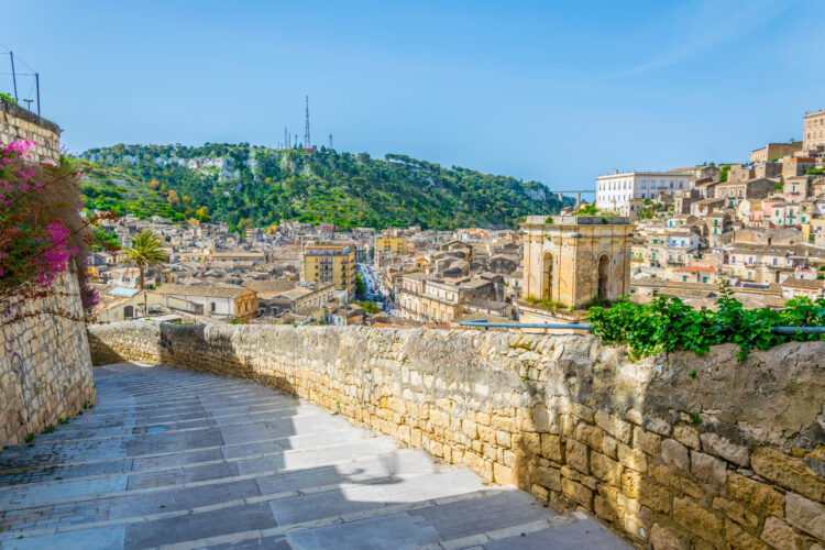 View of a stairway in Modica in Sicily overlooking city beneath it with a famous raised bridge to the right