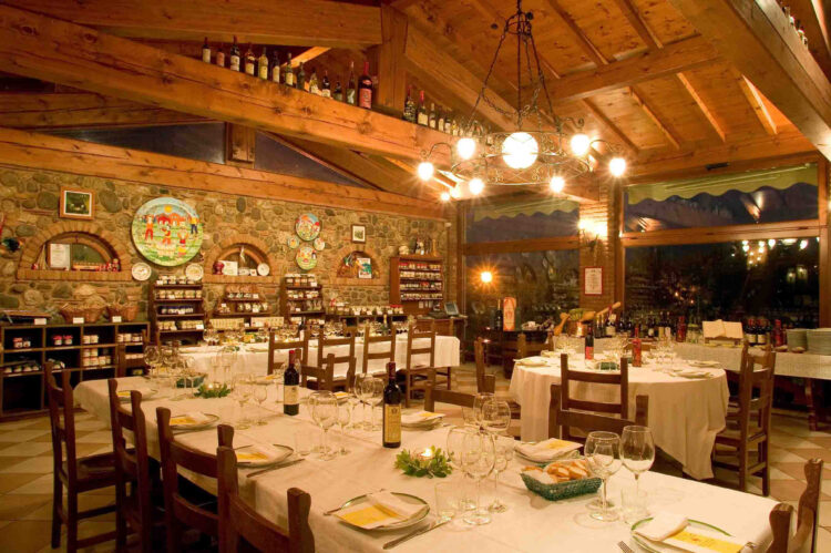Inside the restaurant and tasting rooms of the cantina at redaelli de zinis vineyard. The tables are laid with bread baskets and wine ready for tasting.