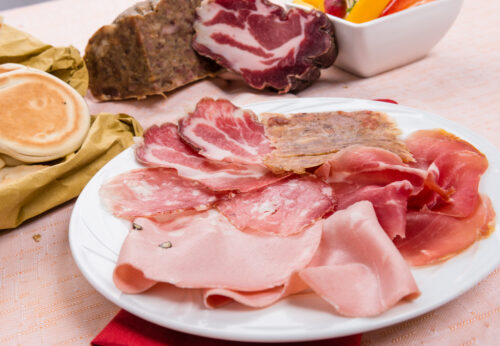 A plate of salami with tigelle, flat bread and fried dumplings Italian food, typical of the kind of starters in Italy