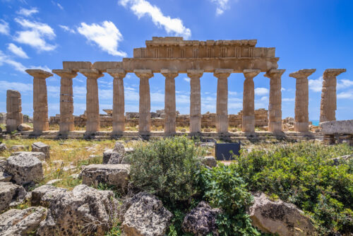 Temple of Apollo on the acropolis of Selinunte ancient city on Sicily Island in Italy, with fallen rocks in the foreground.