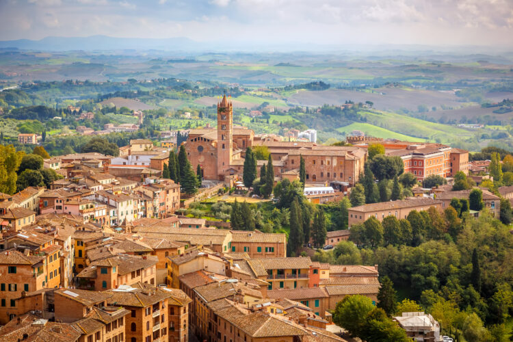 An aerial view over city of Siena, Italy in Tuscany, showing the typical buildings and tiled roofs of the region.