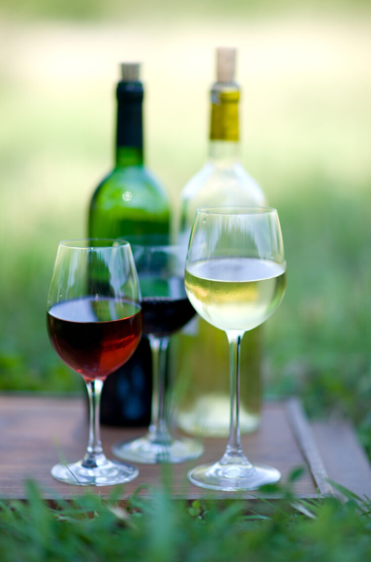 3 wine glasses and two bottles of wine, red and white wine