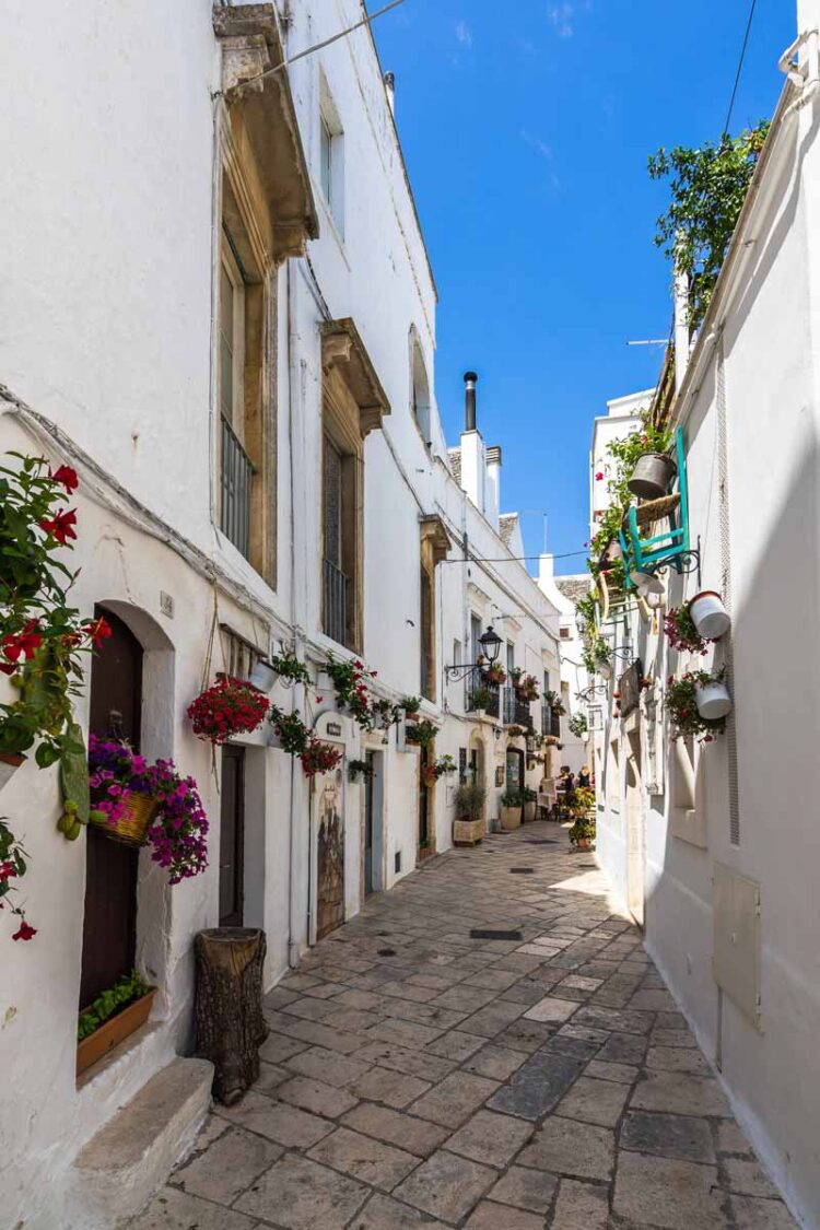 Puglia’s charming town of Locorotondo on the top of a hill in Val D’Itria with its winding streets lined with white houses and flower-filled balconies.