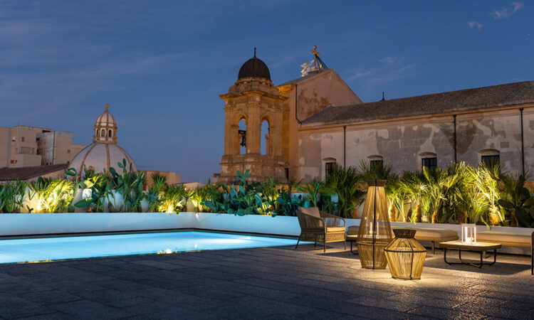 Dome hotel in Sicily lit up at dusk around its pool